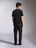 T-shirt Alpinestars Noka CSF, t-shirt à manches courtes, noir, vue de dos du mannequin portant le t-shirt avec un pantalon noir et des baskets, style streetwear décontracté motorsport