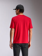 T-shirt Alpinestars Noka CSF, t-shirt à manches courtes, rouge, vue de dos sur mannequin, style streetwear décontracté inspiré du sport automobile, porté avec une casquette noire et un pantalon sombre