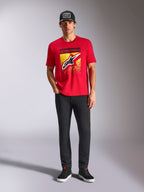 T-shirt Alpinestars Noka CSF, t-shirt à manches courtes, rouge, avec un grand logo Astars à l'avant et un dégradé MX jaune et noir, porté avec un pantalon noir et une casquette noire, style streetwear motorsport décontracté