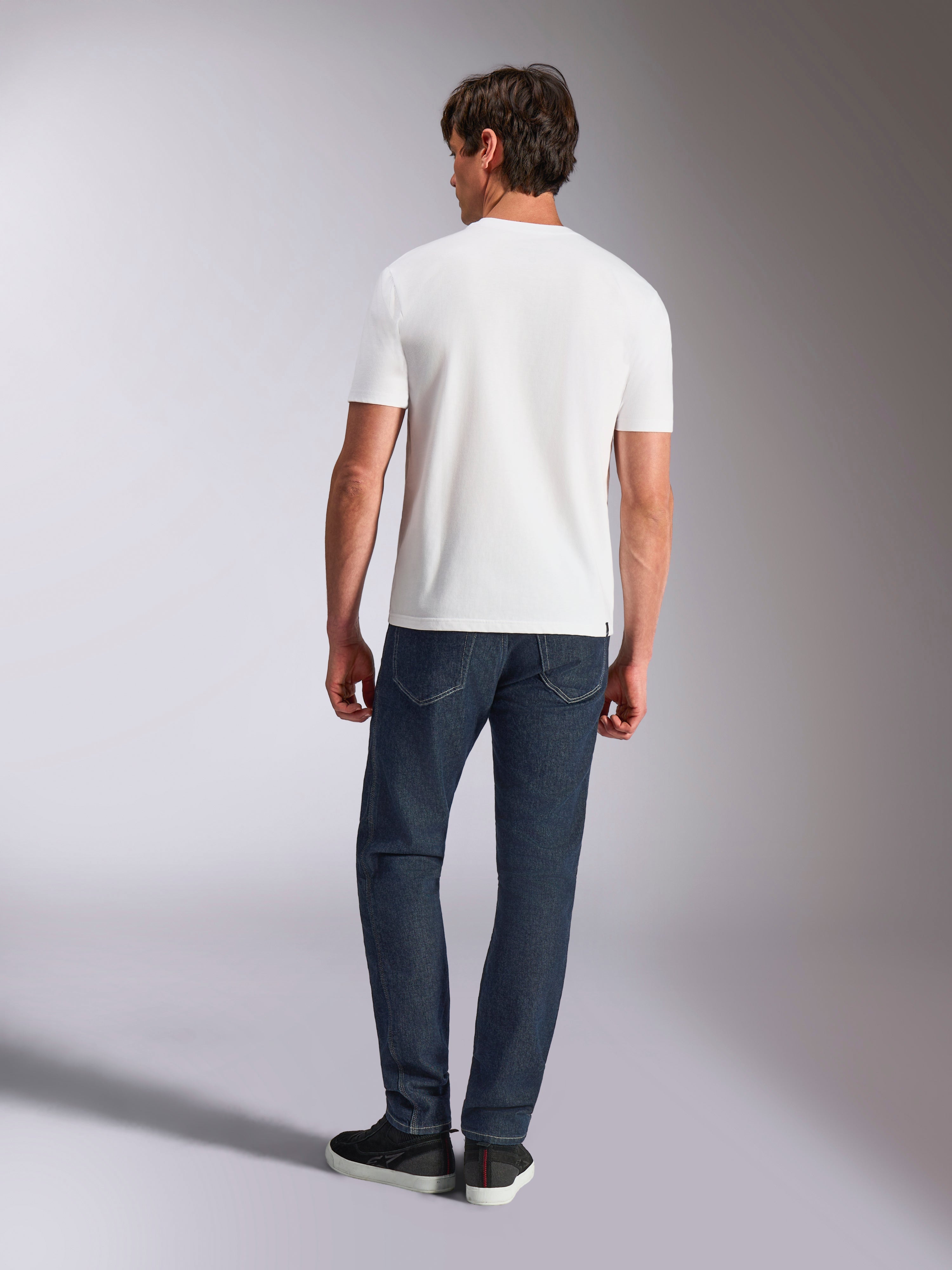 Alpinestars Abus CSF Tee, t-shirt à manches courtes, blanc, vue arrière d'un mannequin portant le t-shirt blanc avec un jean en denim foncé, streetwear décontracté d'inspiration sport automobile