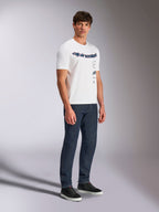 T-shirt Alpinestars Abus CSF, t-shirt à manches courtes blanc, design de logos Alpinestars incurvés empilés, porté par un mannequin homme avec un jean bleu foncé et des baskets noires, style streetwear décontracté motorsport