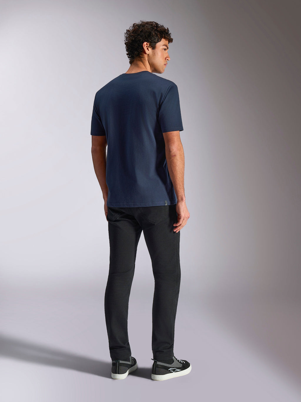T-shirt Alpinestars Trifecta CSF, manches courtes, bleu marine, vue de dos, style sportswear décontracté, porté avec un pantalon noir et des baskets noires