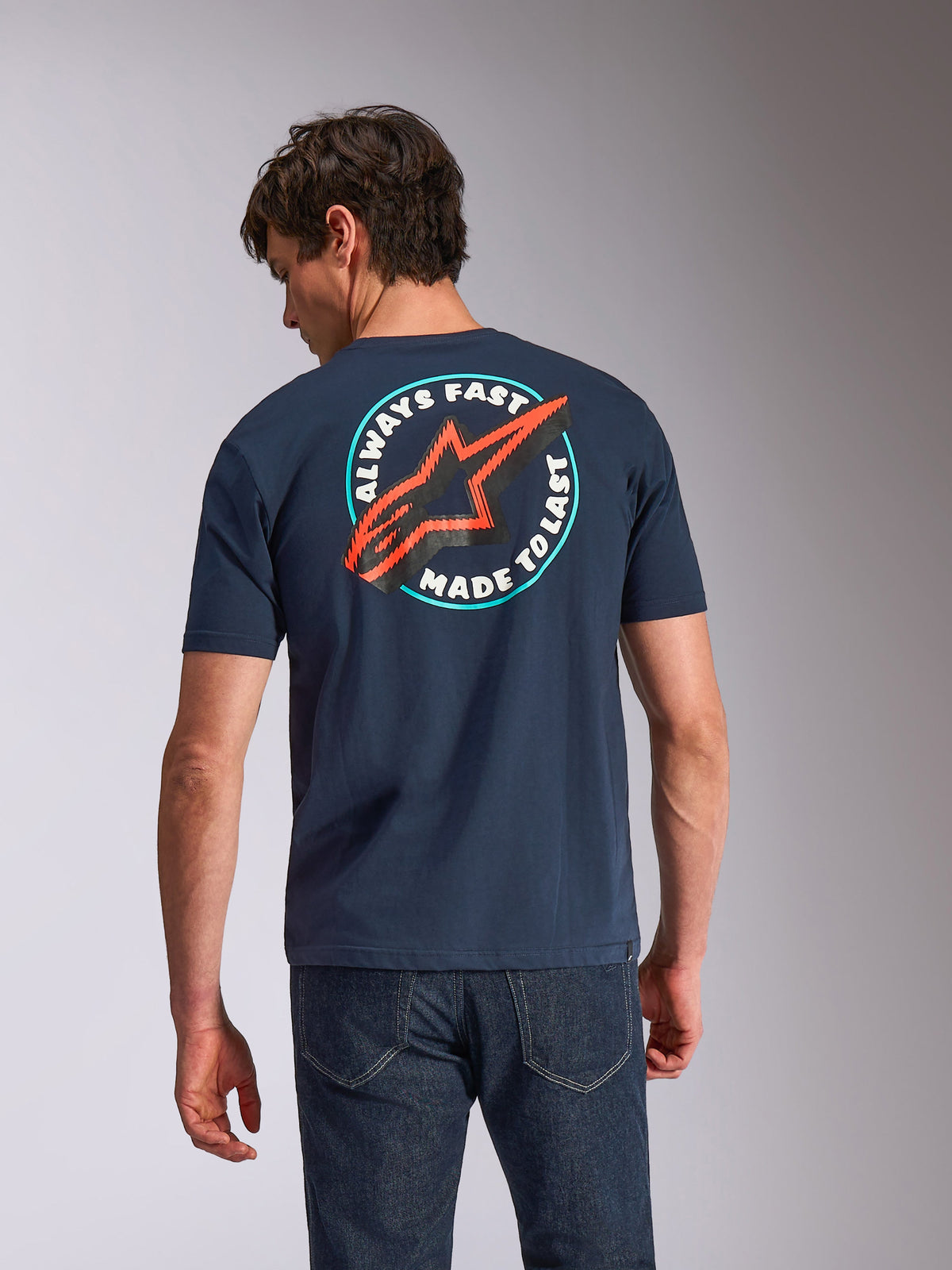 T-shirt Alpinestars Aorbit CSF, t-shirt à manches courtes, bleu marine, vue de dos sur un mannequin avec motif circulaire « Always Fast Made to Last » et logo Astars rouge, streetwear décontracté inspiré du sport automobile