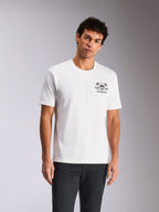 Alpinestars Order CSF Tee, t-shirt à manches courtes, blanc, motif sur la poitrine avec casque et palmiers, porté par un mannequin avec un pantalon sombre, streetwear décontracté inspiré des sports mécaniques