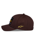 Casquette Snapback Alpinestars Matrix, marron, vue de profil, visière incurvée avec détail de corde noire, écusson brodé à l'avant, logo Astars jaune sur le côté, construction structurée en sergé de coton, couvre-chef motorsport décontracté
