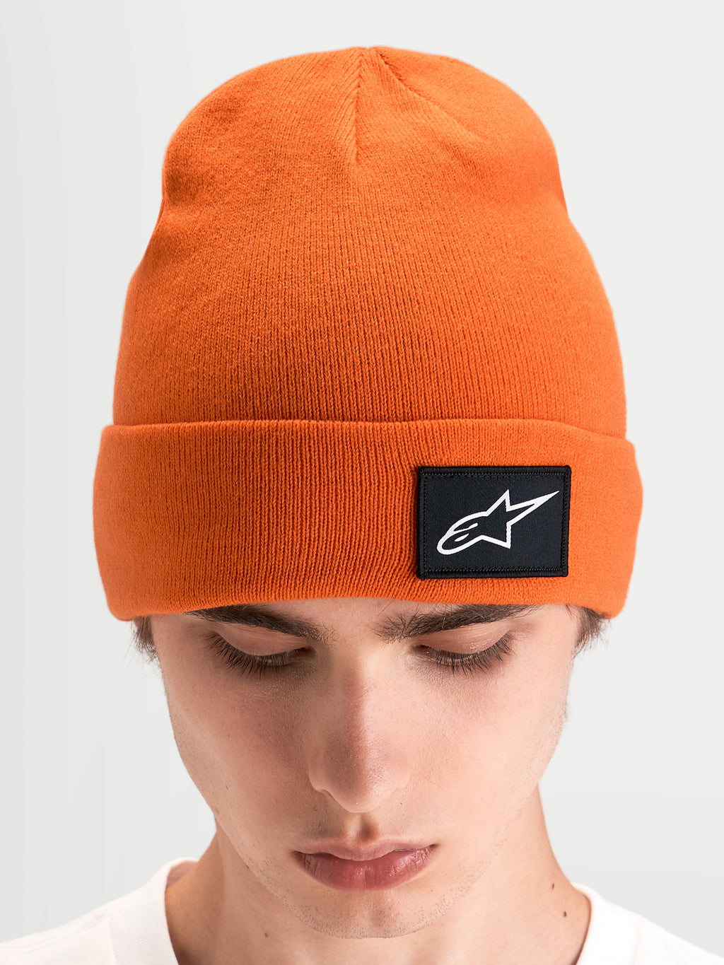 Alpinestars Bonnet Augment Cuff, bonnet sportswear en maille orange à coupe profonde, écusson tissé avec logo Astars noir sur le revers, porté par un modèle
