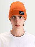 Alpinestars Bonnet Augment Cuff, bonnet sportswear orange vif, porté par un modèle dans une silhouette à coupe profonde avec un écusson logo Astars tissé
