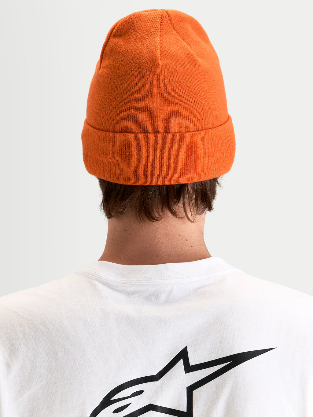 Alpinestars Bonnet Augment Cuff, bonnet en maille orange avec une coupe profonde et un design à revers, vue de dos sur un modèle portant un t-shirt blanc avec un logo Astar noir