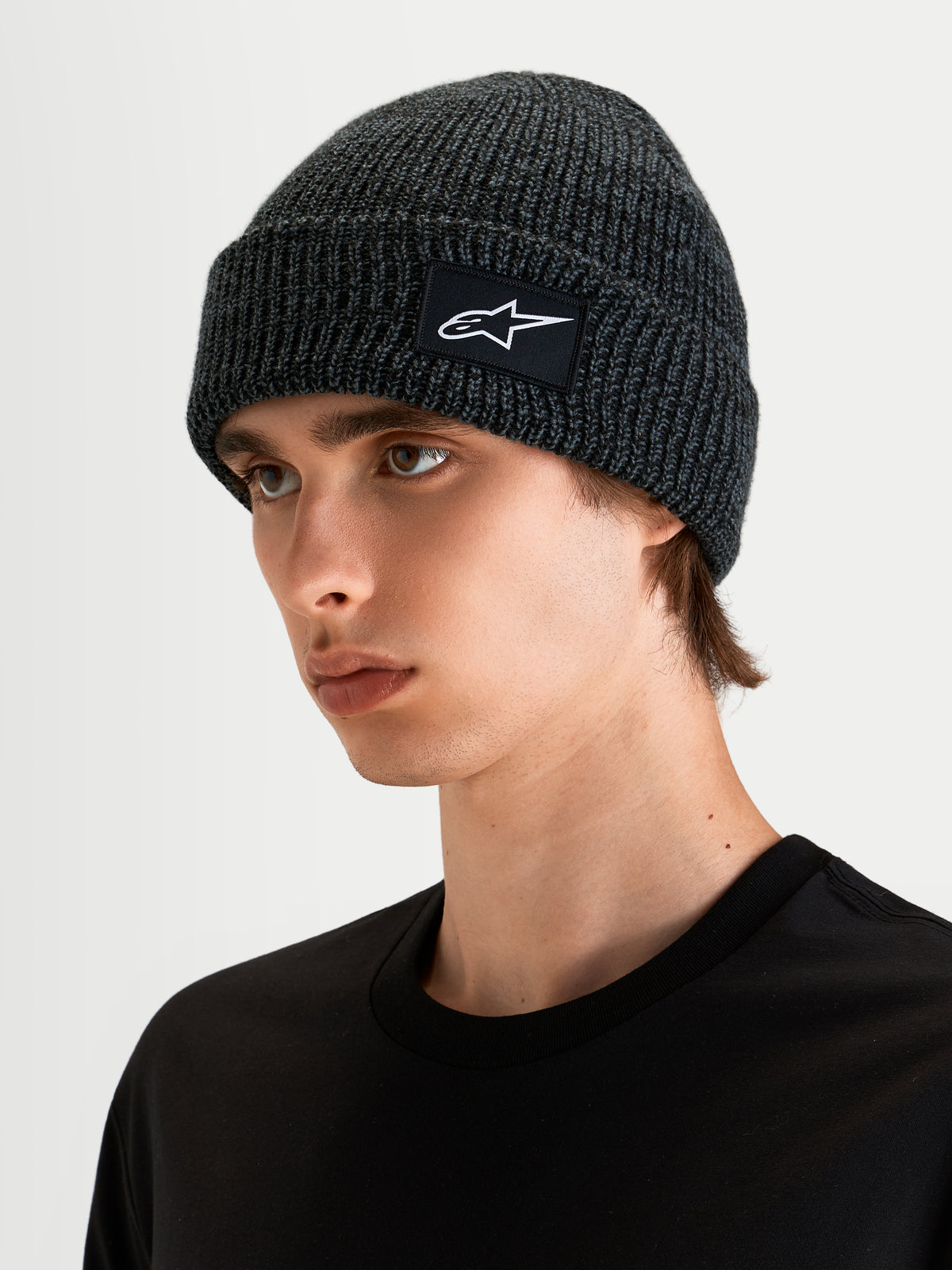 Alpinestars Bonnet Unload Rib Cuff, bonnet sportswear gris anthracite, porté par un modèle montrant le profil à coupe peu profonde et l'écusson tissé SAstars