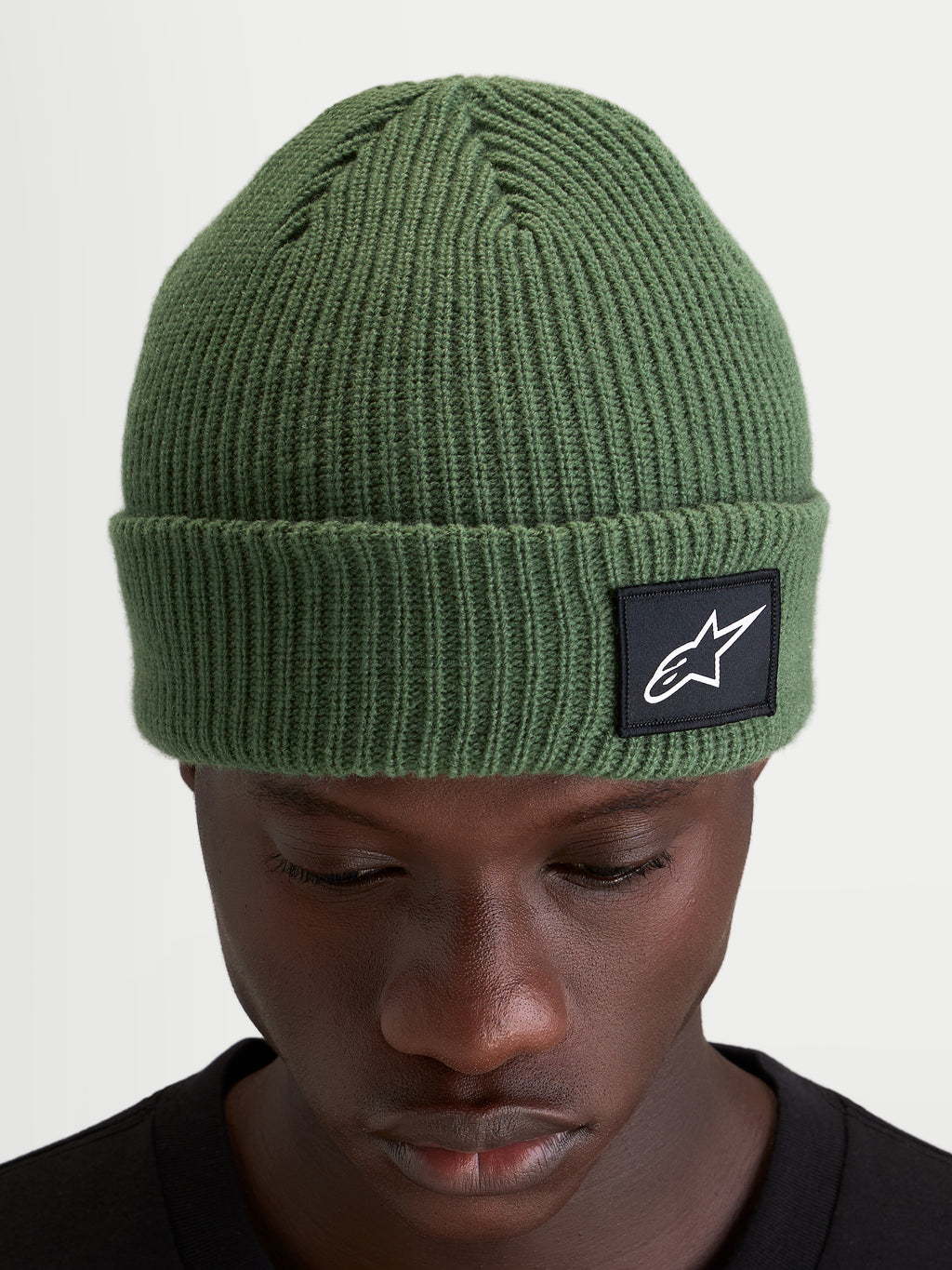 Alpinestars Bonnet Unload Rib Cuff, bonnet sportswear en maille côtelée, vert pois, avec écusson tissé sur le revers porté par un modèle