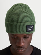 Alpinestars Bonnet Unload Rib Cuff, bonnet sportswear en maille côtelée, vert pois, avec écusson tissé sur le revers porté par un modèle
