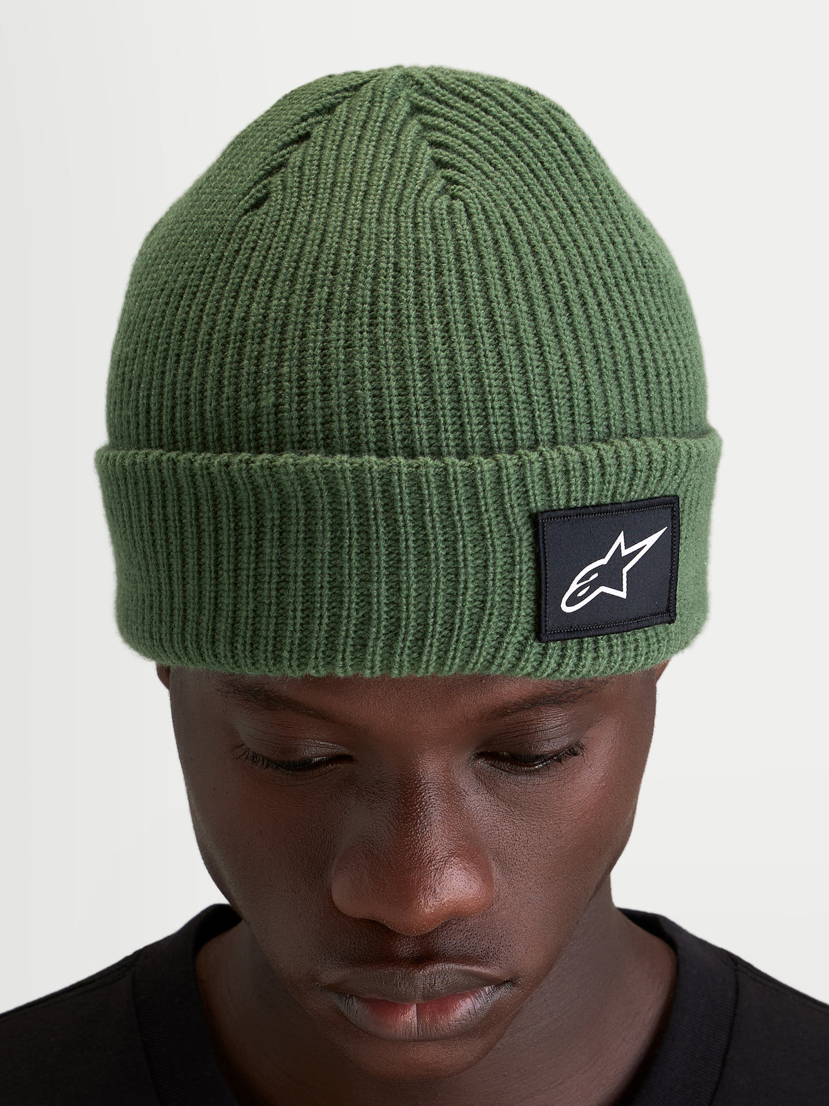 Alpinestars Bonnet Unload Rib Cuff, bonnet sportswear en maille côtelée, vert pois, avec écusson tissé sur le revers porté par un modèle