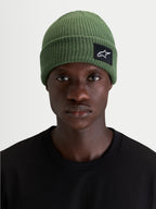 Bonnet Unload Rib Cuff d'Alpinestars, bonnet sportswear en maille côtelée vert, coupe peu profonde avec écusson tissé SAstars sur le devant, porté par un modèle