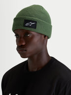 Bonnet Unload Rib Cuff d'Alpinestars, bonnet casual vert pois porté par un modèle, avec maille jersey tricotée et écusson tissé SAstars noir et blanc