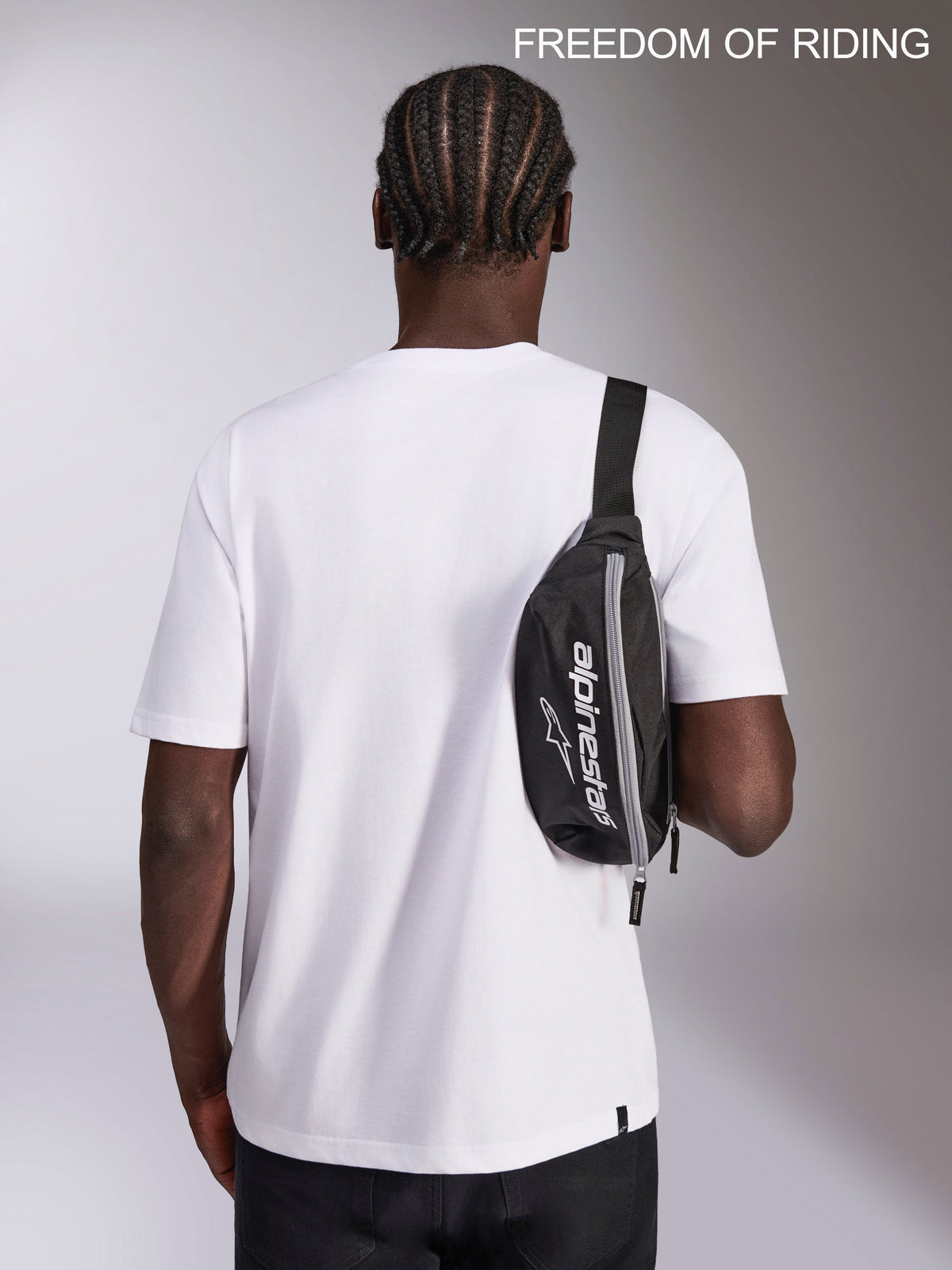 Alpinestars Sac Banane Only Linear, sacoche de hanche sportswear urbaine, noir et blanc, capacité 2L, 100% polyester avec logo Alpinestars, porté en bandoulière sur un modèle pour les déplacements quotidiens.