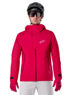 Alpinestars A-Dura Elite Waterproof Jacket, veste de pluie pour VTT, rouge fluo, col montant avec logo Alpinestars blanc, fermetures éclair noires, portée avec gants assortis et casque de vélo noir, équipement de cyclisme technique imperméable