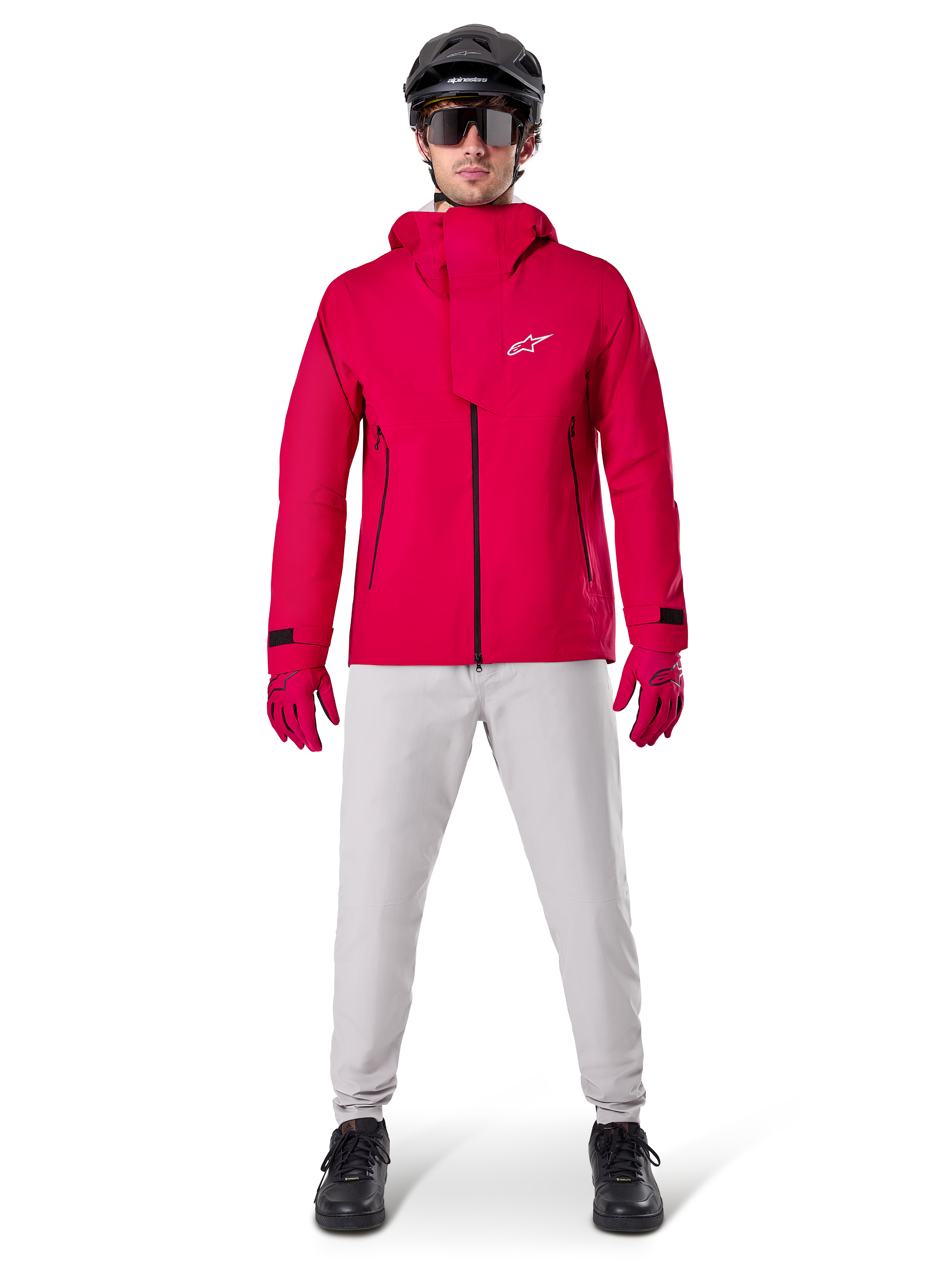 Veste imperméable Alpinestars A-Dura Elite, rouge fluo, veste technique de VTT portée avec un casque de VTT noir, des lunettes de soleil, des gants rouges assortis et un pantalon gris clair, vue d'ensemble de l'équipement de cyclisme toutes saisons