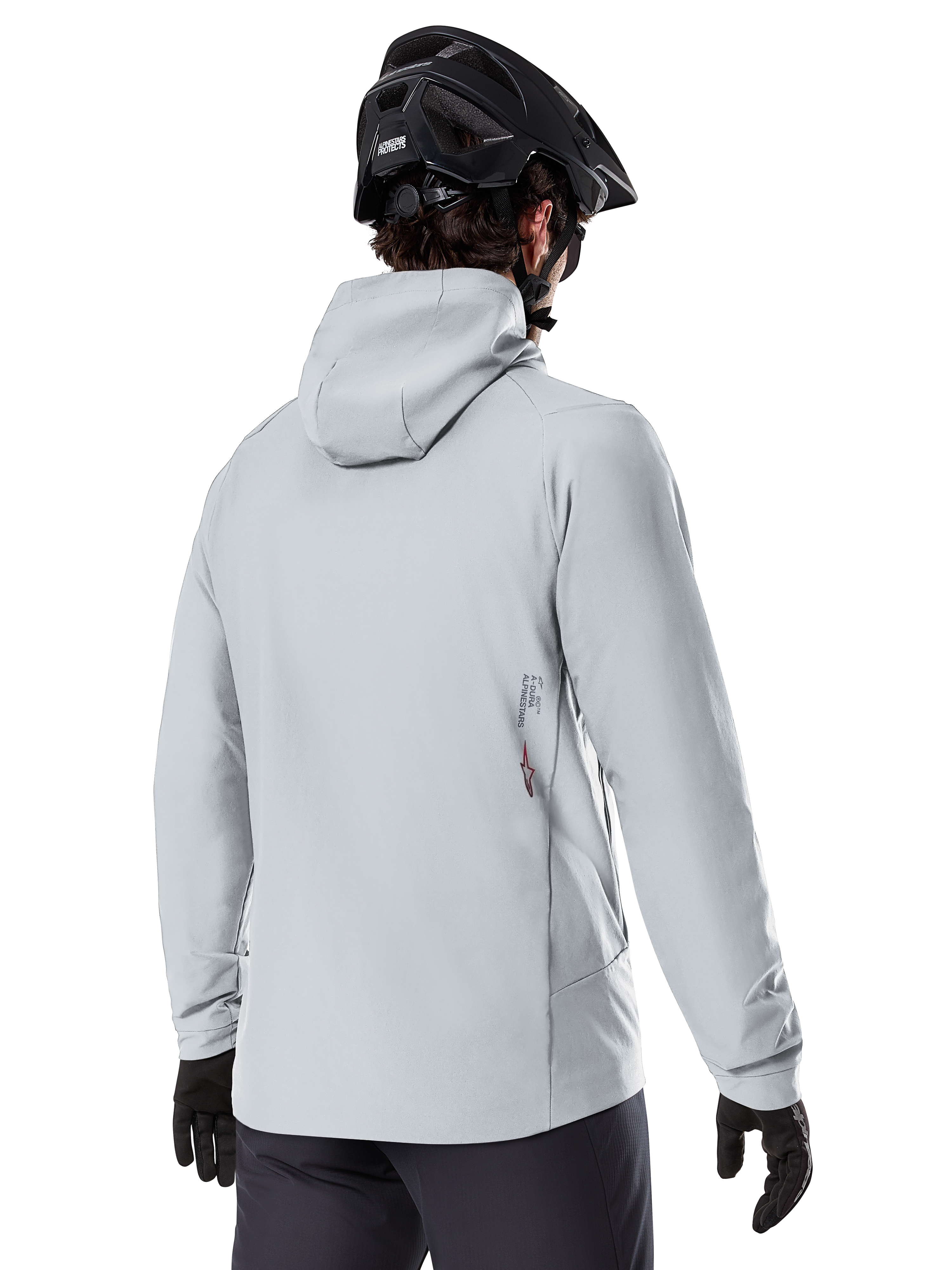 Veste thermique Alpinestars A-Dura, Gris Titanium, vue de dos d'un cycliste portant la veste isolante à capuche, associée à un casque de VTT noir et des gants noirs, avec un petit logo Alpinestars en bas du dos, conçue pour le VTT par temps froid.