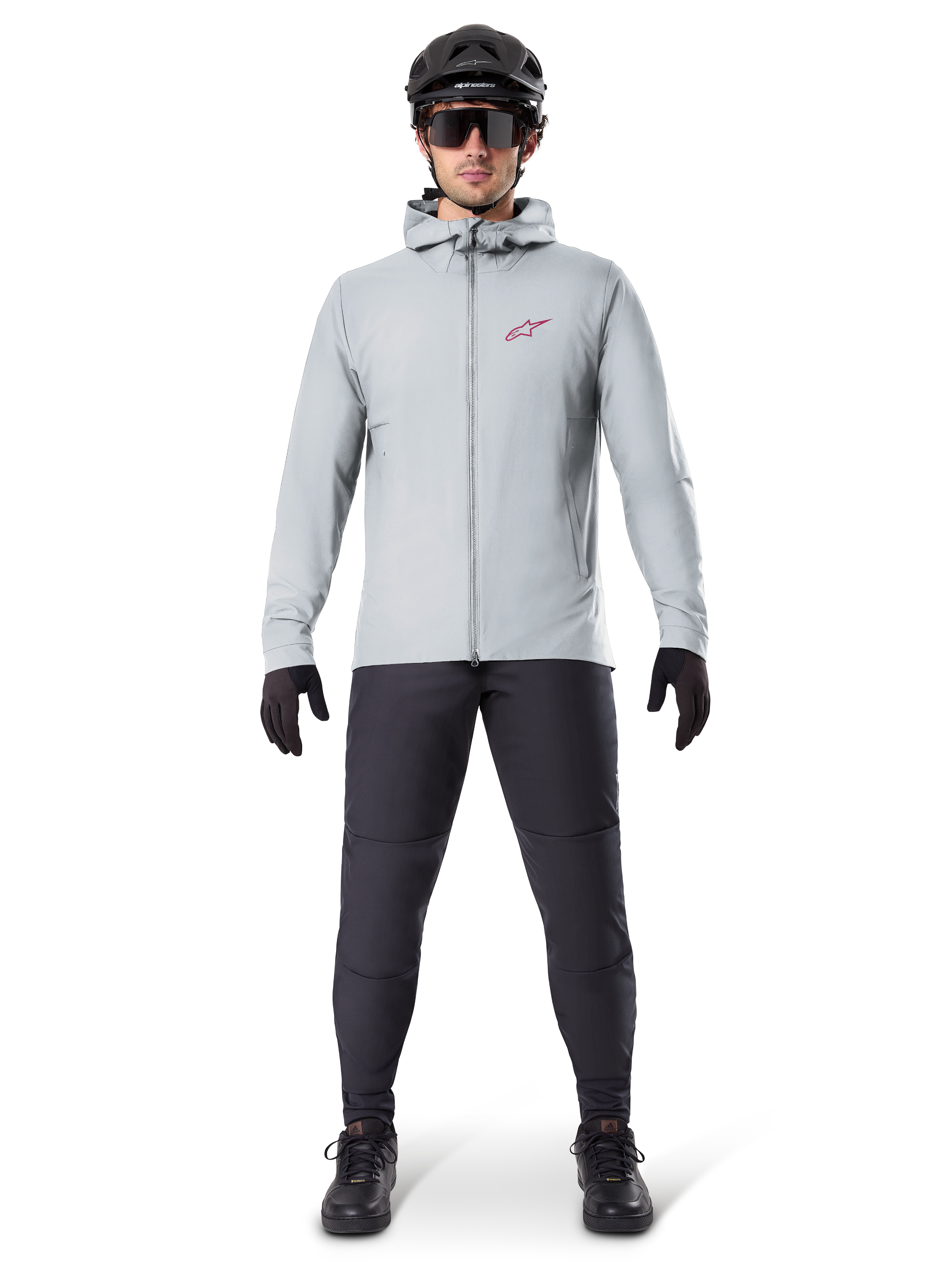Veste thermique Alpinestars A-Dura, gris titane, veste de cyclisme portée avec un pantalon de VTT noir, des gants et un casque, dotée d'un petit logo étoile rouge sur la poitrine et d'une fermeture éclair frontale intégrale, équipement isolant léger pour le tout-terrain.