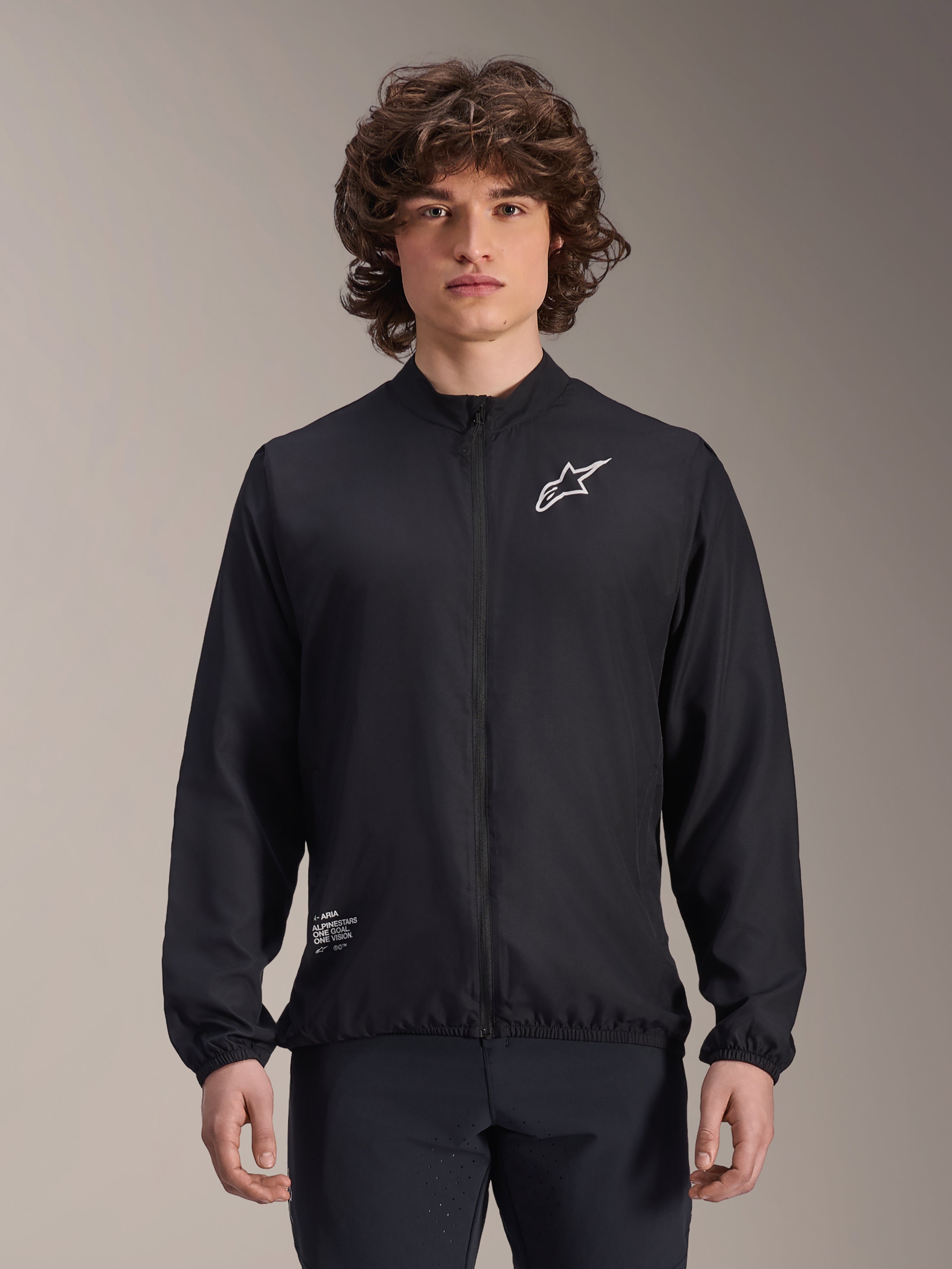 Veste coupe-vent Alpinestars A-Aria, noire, veste de cyclisme légère, avec logo Astars blanc sur la poitrine et marquage en bas à droite, fermeture éclair intégrale, col montant, poignets et ourlet élastiques, coupe performance pour les sports de plein air