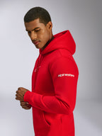 Sweat à capuche Alpinestars Frontal, rouge, sweat à capuche en polaire porté par un mannequin, avec lettrage Alpinestars blanc sur la manche, logo frontal, poche kangourou et capuche à cordon de serrage, design décontracté inspiré du sport automobile