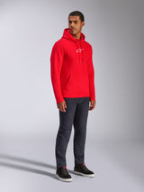 Alpinestars Sweat à capuche Frontal, rouge, mannequin homme portant un sweat à capuche en polaire avec logo A-star blanc sur la poitrine, poche kangourou, capuche à cordon de serrage, associé à un jean en denim foncé, style streetwear décontracté d'inspiration sport mécanique
