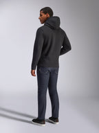 Alpinestars Blaze V3 Hoodie, vue de dos d'un homme portant le sweat à capuche noir, associé à un jean foncé et des baskets noires, style streetwear décontracté inspiré du sport automobile