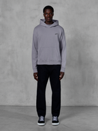 Alpinestars Essentials Ageless Hoodie, Argent, mannequin homme portant un style streetwear décontracté, petit logo Alpinestars noir sur la poitrine, poche kangourou à l'avant, design minimaliste, associé à un pantalon noir et des baskets.