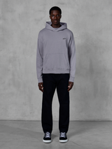 Alpinestars Essentials Ageless Hoodie, Argent, mannequin homme portant un style streetwear décontracté, petit logo Alpinestars noir sur la poitrine, poche kangourou à l'avant, design minimaliste, associé à un pantalon noir et des baskets.