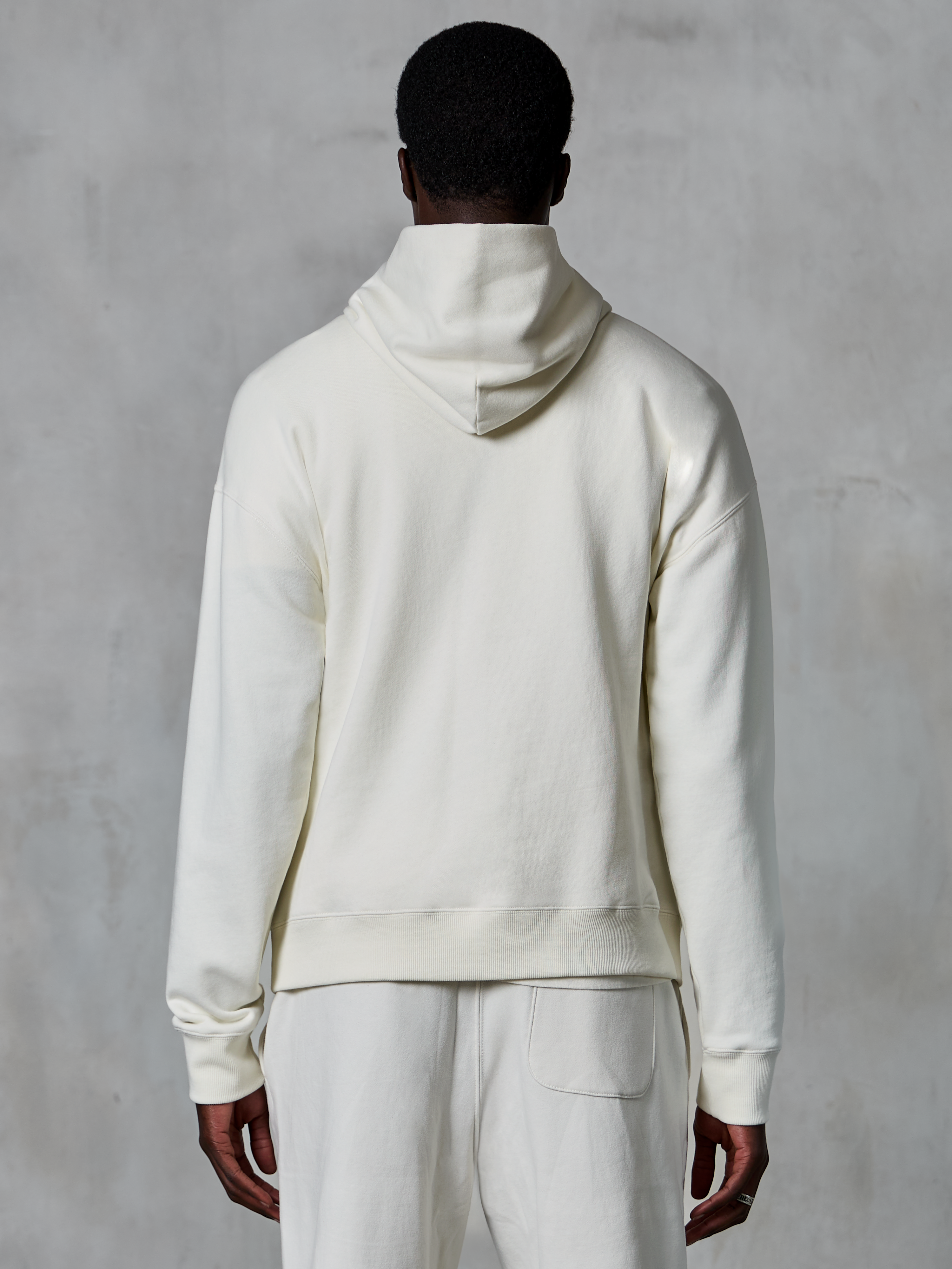 Sweat à capuche Alpinestars Essentials Ageless, sweat à capuche blanc cassé, vue de dos sur modèle, design minimaliste et épuré, pantalon décontracté assorti, coupe décontractée pour un confort quotidien