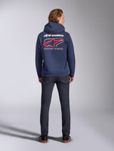 Alpinestars Formulation Hoodie in Navy, back view, featuring large white Alpinestars wordmark and red logo with 'RACING AHEAD' print, casual motorsport-inspired streetwear paired with dark jeans