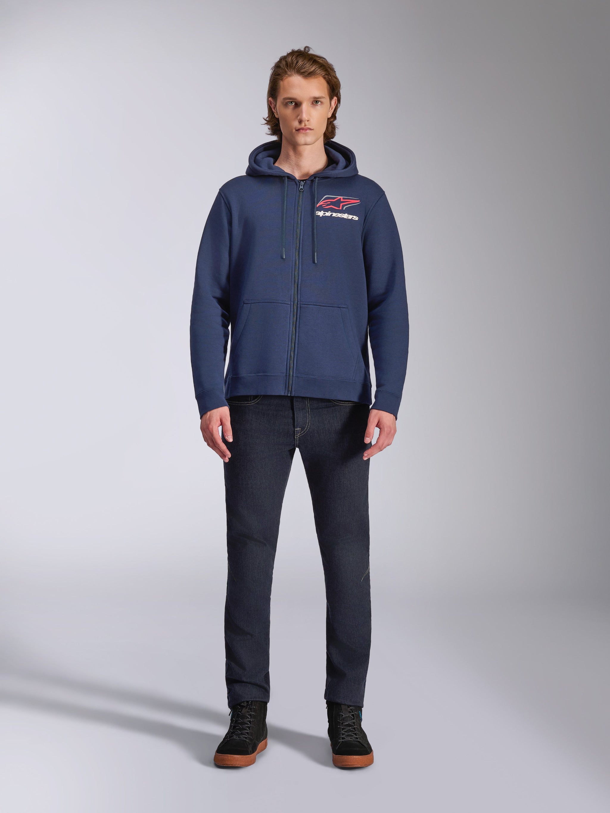 Alpinestars Formulation Hoodie, Navy Blue zip-up fleece hoodie, worn by male model with dark blue jeans, featuring red and white chest logo, mesh-lined hood with drawcords, casual motorsport streetwear