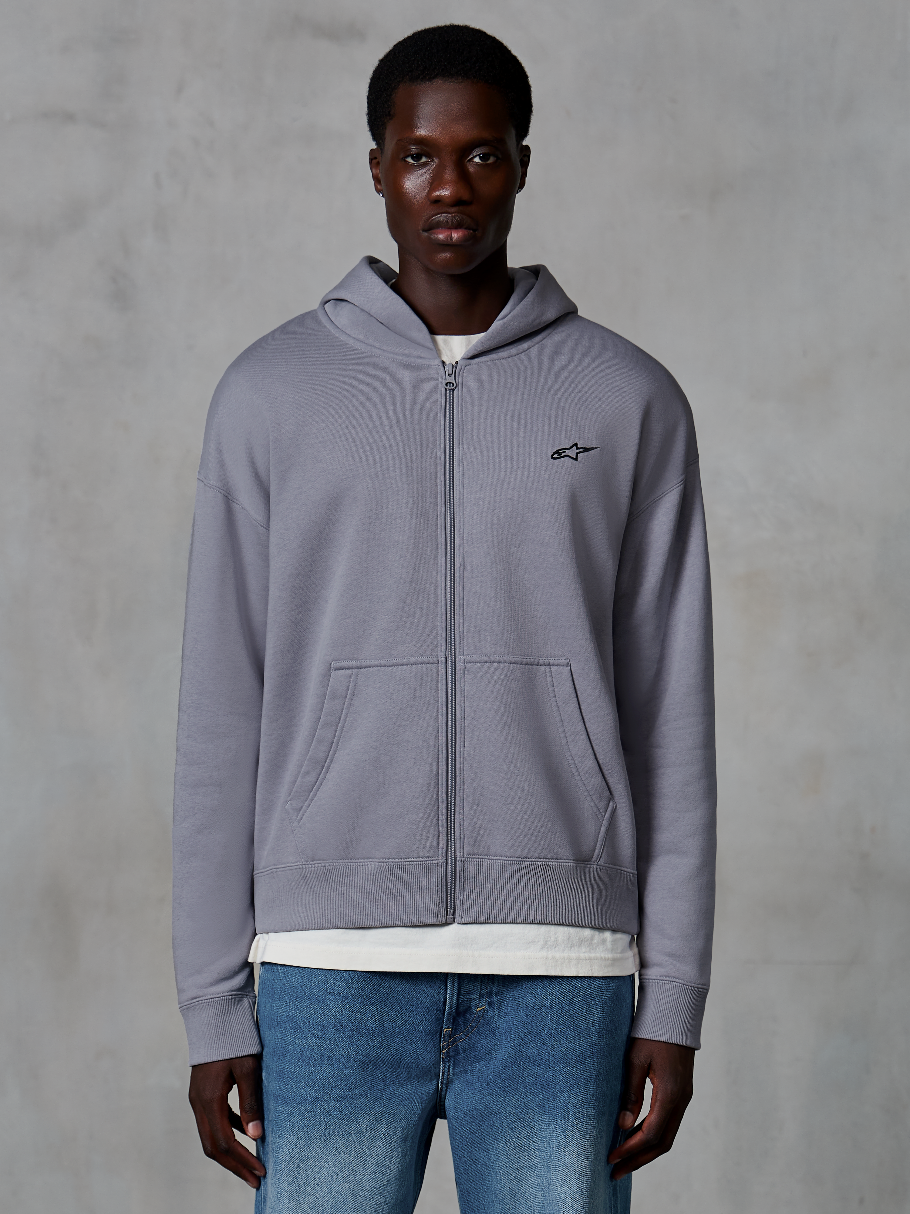Sweat à capuche zippé Alpinestars Essentials Ageless, Argent, streetwear décontracté porté par un mannequin, polaire zippée avec petit logo Astars noir sur la poitrine, poches kangourou, coupe décontractée