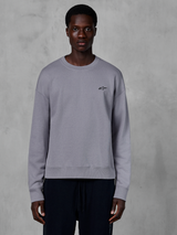 Alpinestars Essentials Ageless Crew, sweat-shirt à col rond argenté porté par un mannequin, avec un petit logo étoile noir sur la poitrine, coupe décontractée avec poignets et ourlet côtelés, style streetwear décontracté inspiré du sport automobile