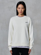 Alpinestars Essentials Ageless Crew, sweat-shirt à col rond, blanc cassé, avec un petit logo Alpinestars noir sur la poitrine, vêtement lifestyle décontracté porté par une femme