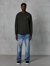 T-shirt à manches longues Alpinestars Essentials Ageless, noir, avec un petit logo étoile blanc sur la poitrine, coupe décontractée, streetwear décontracté inspiré du sport automobile, porté avec un jean bleu clair