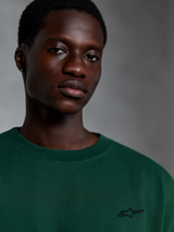 Alpinestars Essentials Ageless SS Tee, Pine Green Short Sleeve T-Shirt, Close-up of model wearing green organic cotton tee with small embroidered logo, casual streetwear design