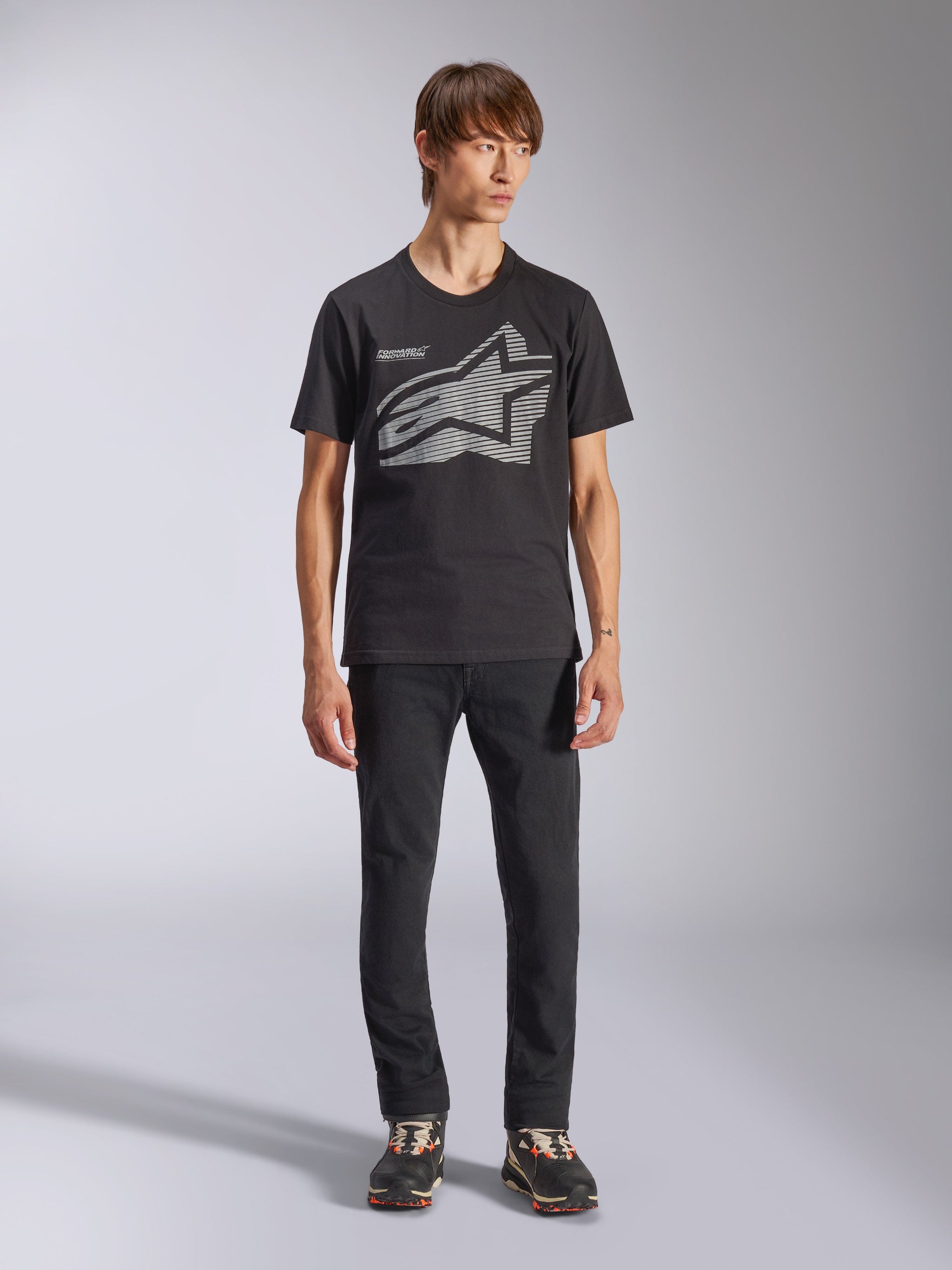Alpinestars Fasting CSF Tee, T-shirt à manches courtes, noir, grand logo Astars géométrique gris, porté par un mannequin avec un pantalon noir et des baskets, style streetwear décontracté motorsport