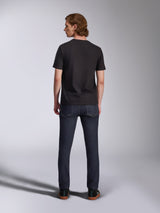 T-shirt Global CSF Alpinestars, t-shirt à manches courtes noir, vue de dos d'un mannequin homme portant le t-shirt avec un jean en denim foncé, streetwear décontracté inspiré du sport automobile