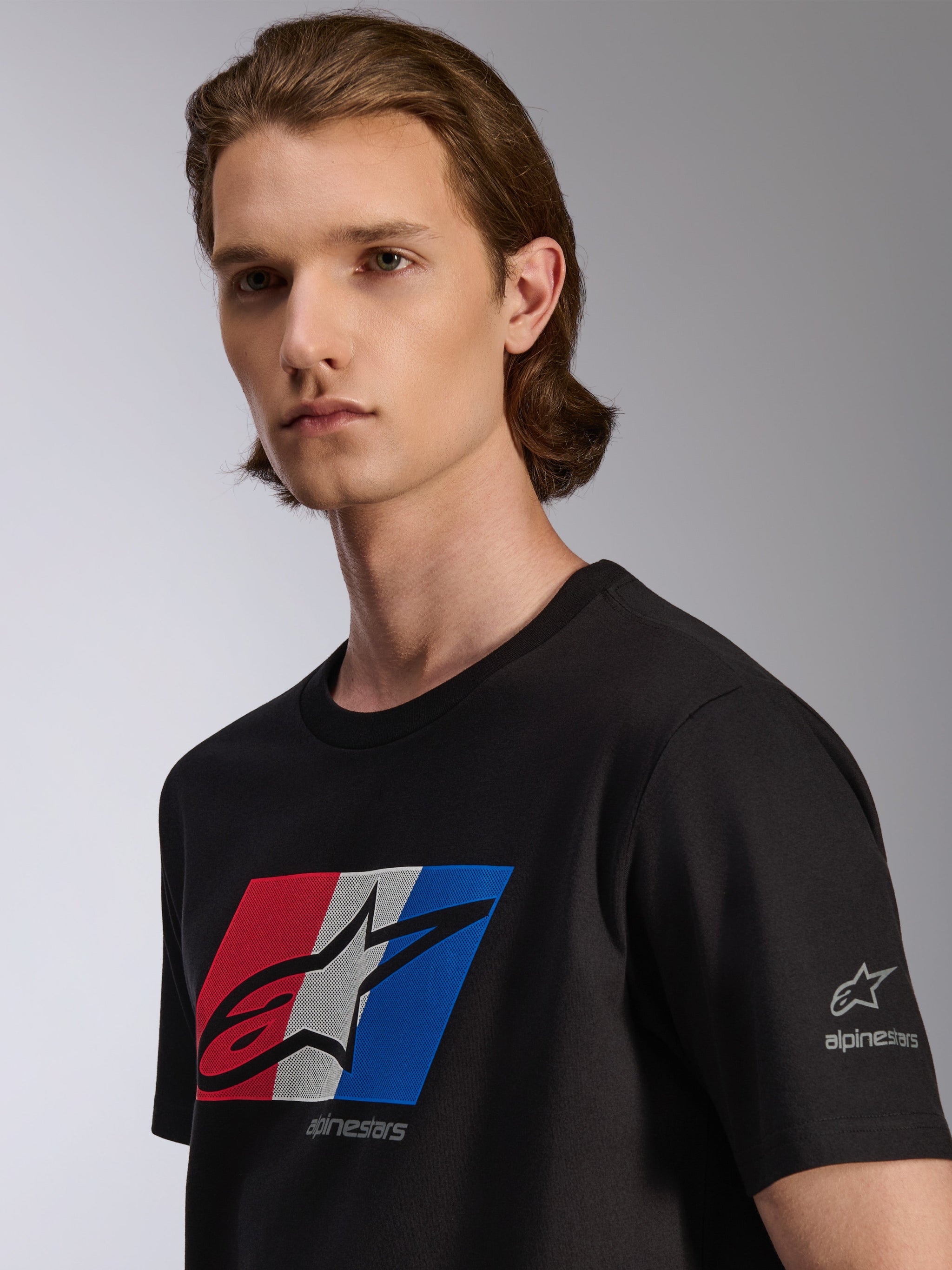 Alpinestars Global CSF Tee, t-shirt à manches courtes, noir, graphique rouge, blanc et bleu avec logo noir ombré, vue détaillée sur mannequin, streetwear décontracté inspiré du sport automobile
