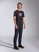 Alpinestars Global CSF Tee, t-shirt à manches courtes, noir avec graphique de logo rouge, blanc et bleu, streetwear motorsport décontracté, photo en pied d'un mannequin portant un jean foncé et des baskets noires