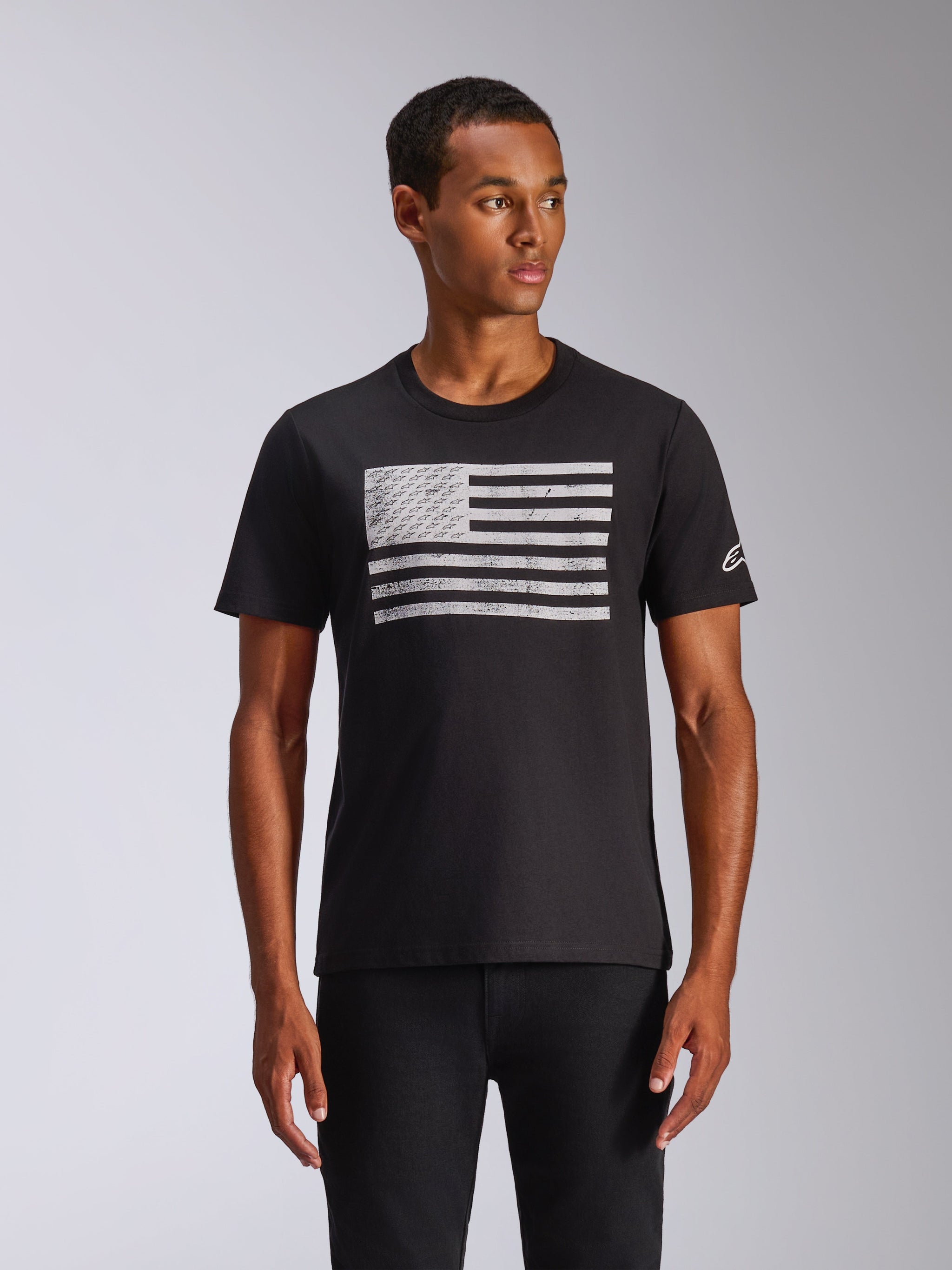 Alpinestars Waving CSF Tee, Short Sleeve T-Shirt, Black, Distressed White Flag Graphic with Integrated Logos, Small White Logo on Sleeve, worn by a model, Casual Motorsport Streetwear