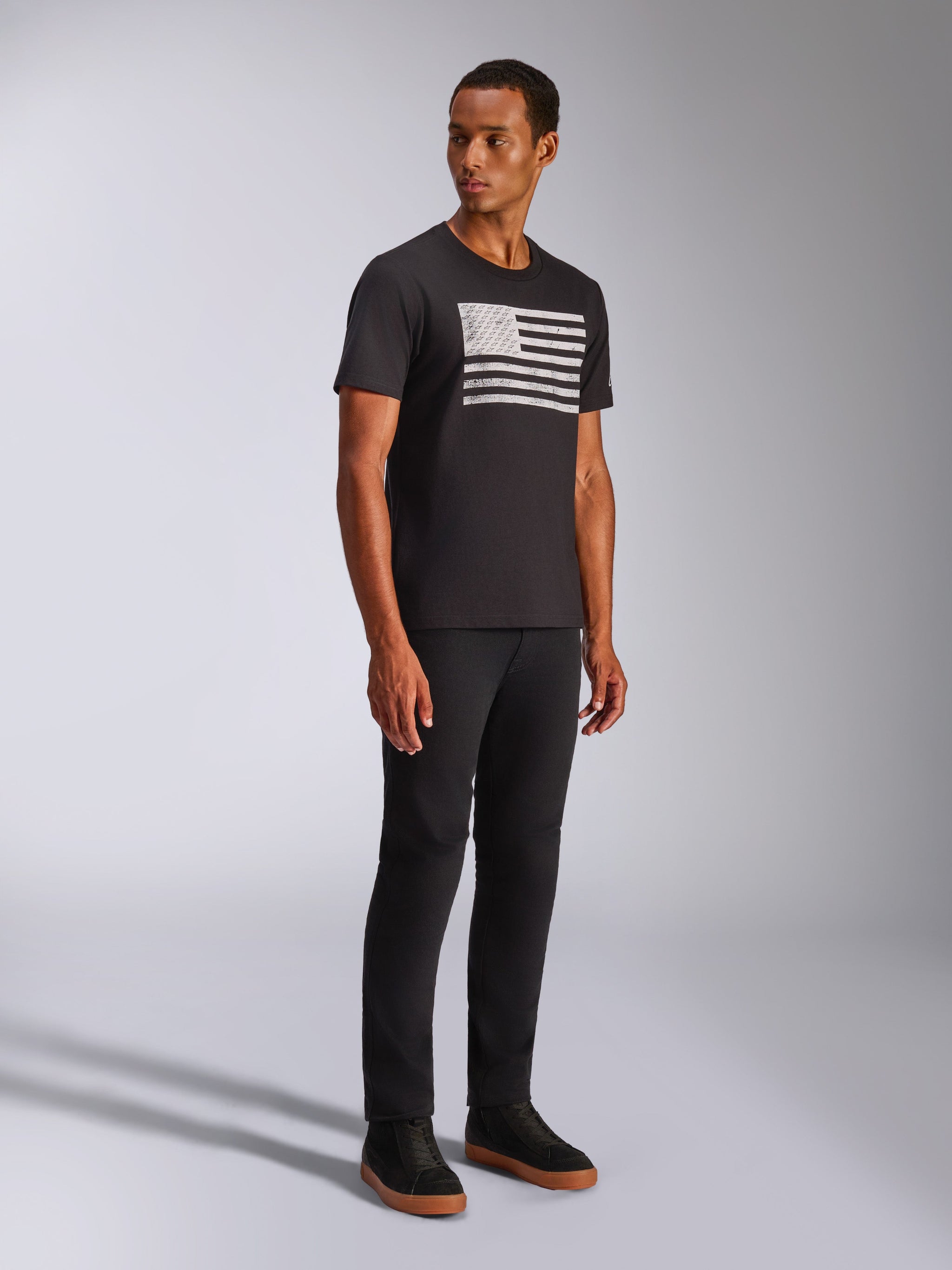 Alpinestars Waving CSF Tee, Short Sleeve T-Shirt, Black, White waving flag-inspired Blaze 2.0 graphic on chest, worn by model with black pants and black shoes, Casual Motorsport Streetwear