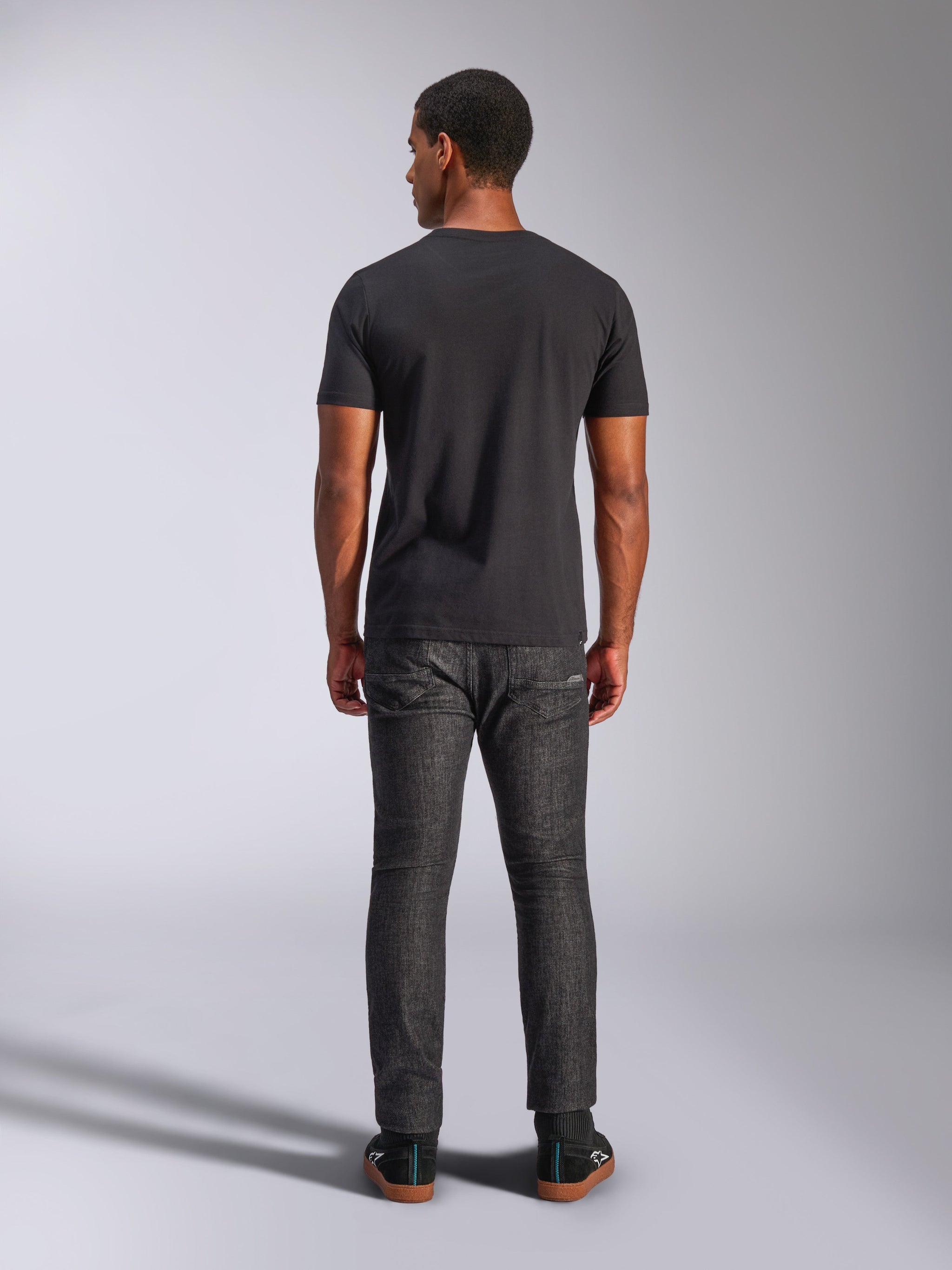 Alpinestars Tech Boot CSF Tee, Short Sleeve T-Shirt, Black, Back view on model, worn with dark gray jeans and black sneakers, casual motorsport-inspired streetwear