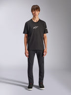 T-shirt Alpinestars Frontal CSF, T-shirt à manches courtes, noir, logo Alpinestars blanc sur la poitrine, porté par un mannequin avec un pantalon noir et des chaussures noires, vêtement de sport performant et décontracté