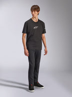Alpinestars Frontal CSF Tee, t-shirt à manches courtes, noir, logo Astars blanc sur la poitrine, porté par un mannequin avec un jean foncé et des baskets noires, streetwear de performance décontracté