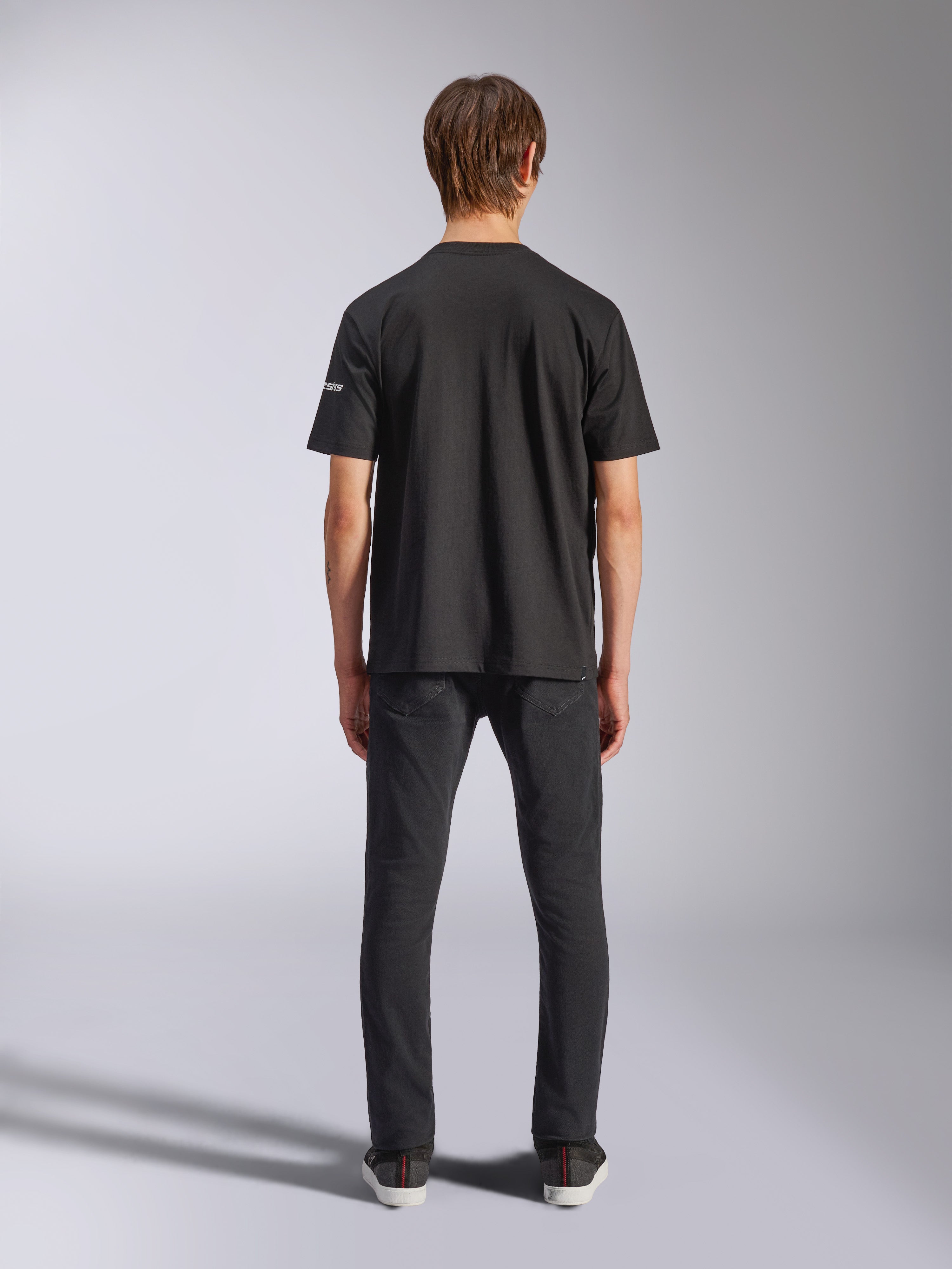 T-shirt Alpinestars Frontal CSF, t-shirt à manches courtes, noir, vue arrière sur mannequin portant un jean noir, vêtement streetwear décontracté et performant avec petit logo blanc sur la manche