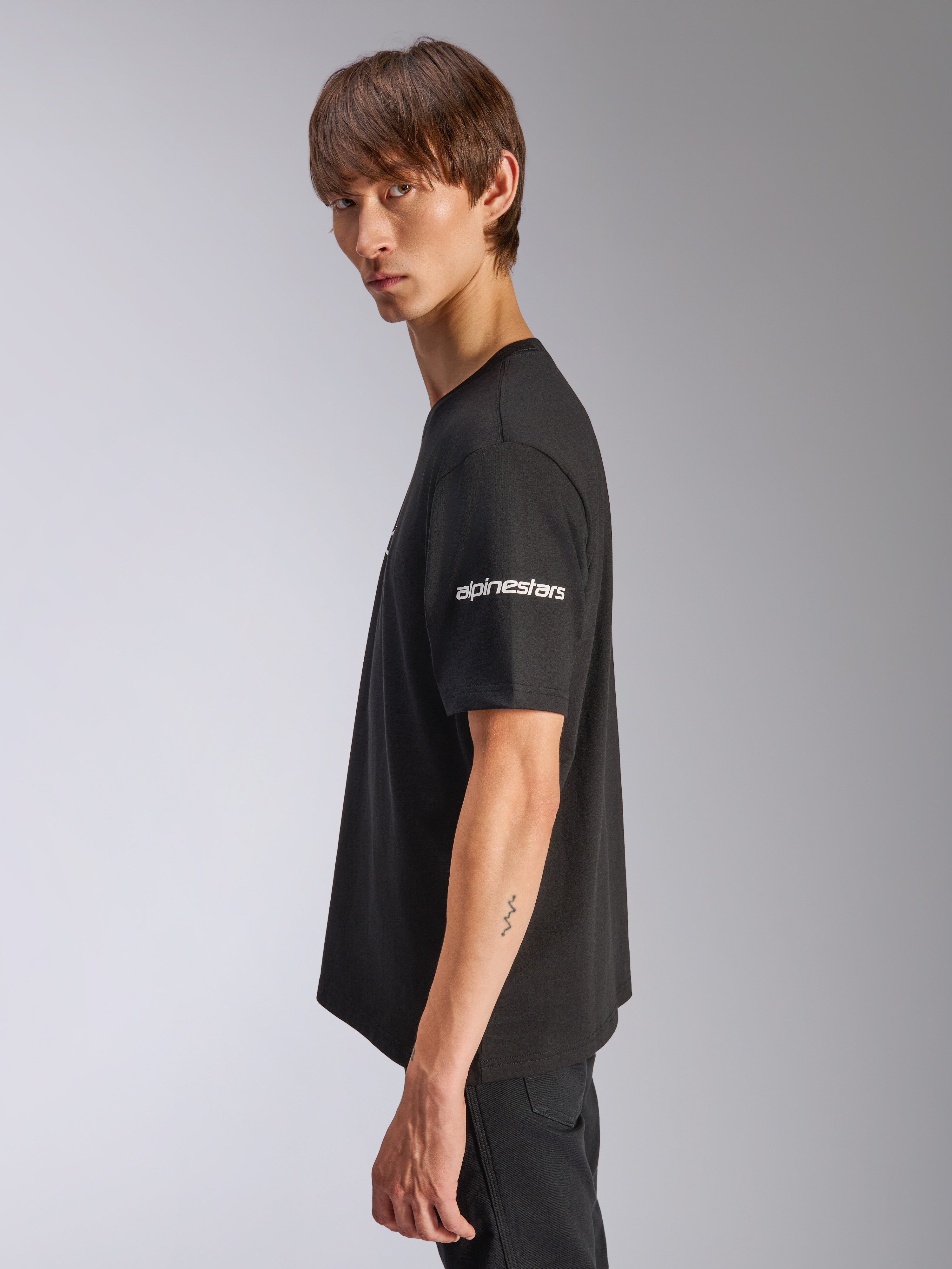 T-shirt Alpinestars Frontal CSF, t-shirt à manches courtes, noir, logo Alpinestars blanc sur la manche, porté par un mannequin en vue de profil, streetwear de performance motorsport décontracté