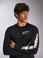Alpinestars Trackside CSF Tee - Long Sleeve, noir et blanc, t-shirt à manches longues avec un petit logo étoile blanc sur la poitrine et un lettrage blanc imposant sur la manche gauche, streetwear décontracté inspiré du sport automobile porté par un mannequin aux bras croisés