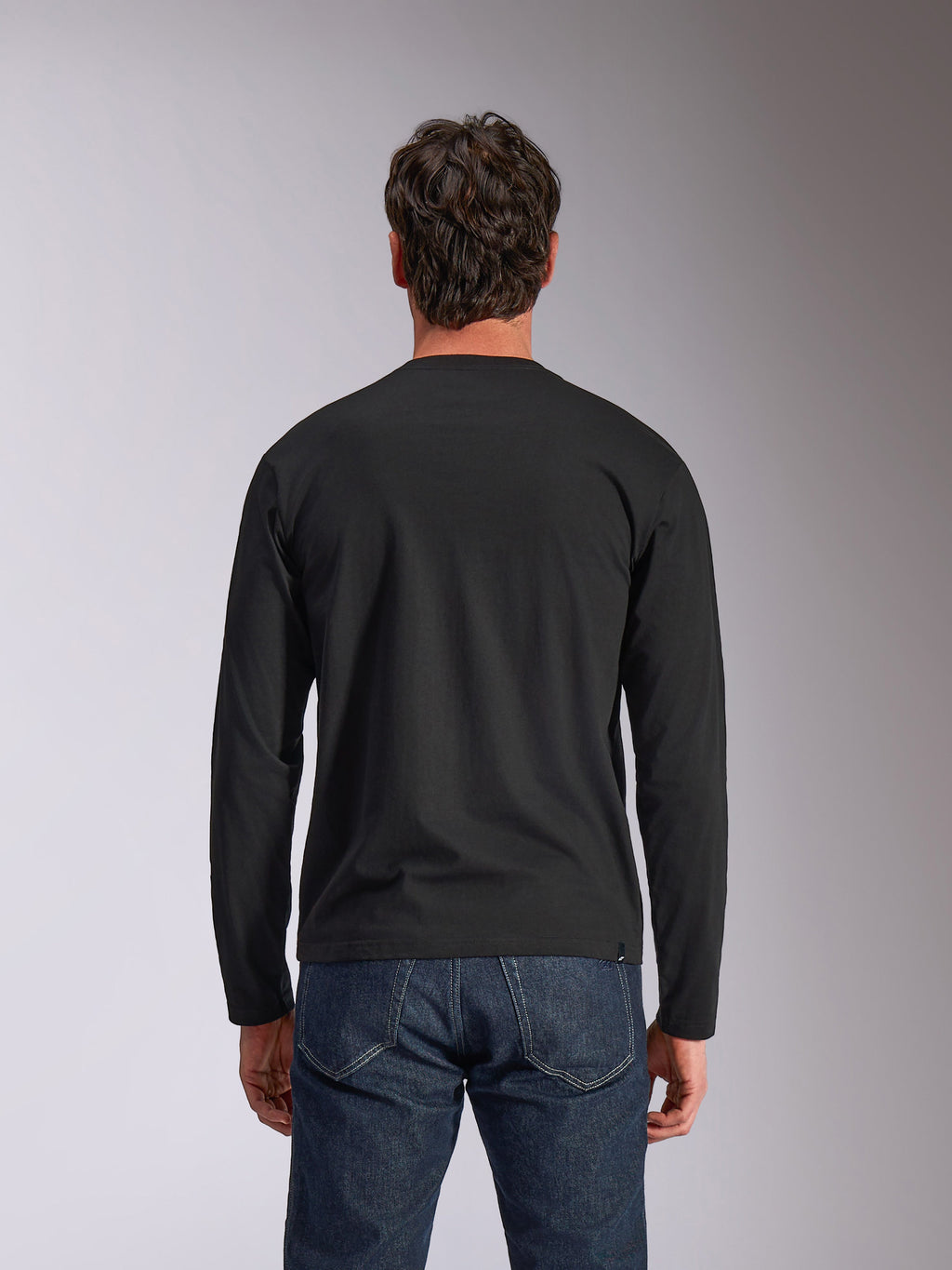 T-shirt à manches longues Alpinestars Trackside CSF, noir, vue de dos, porté avec un jean en denim bleu foncé, streetwear décontracté inspiré du sport automobile